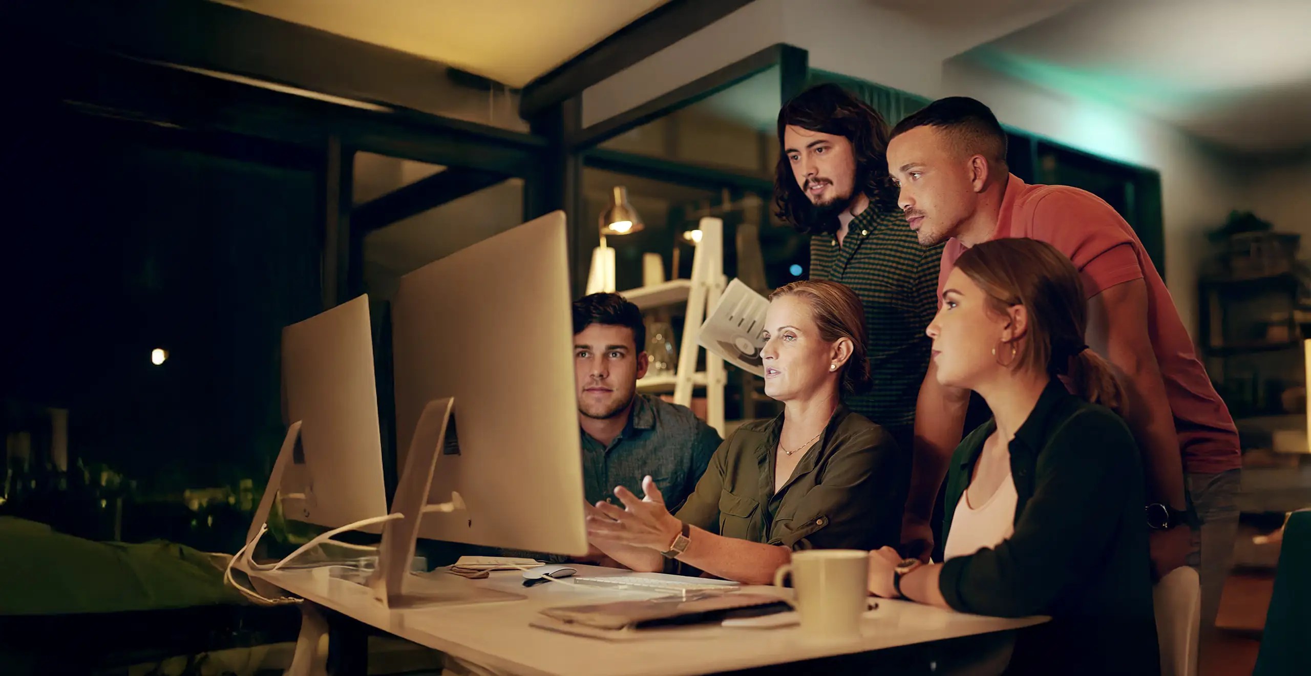Group of professionals collaborating while viewing data on a large computer screen in a modern office