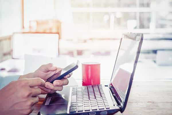 person at a laptop using phone