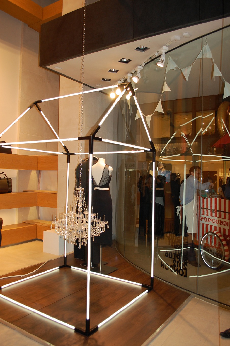 Estructura luminosa en forma de casa con maniquí y lámpara de araña en el escaparate de DAKS