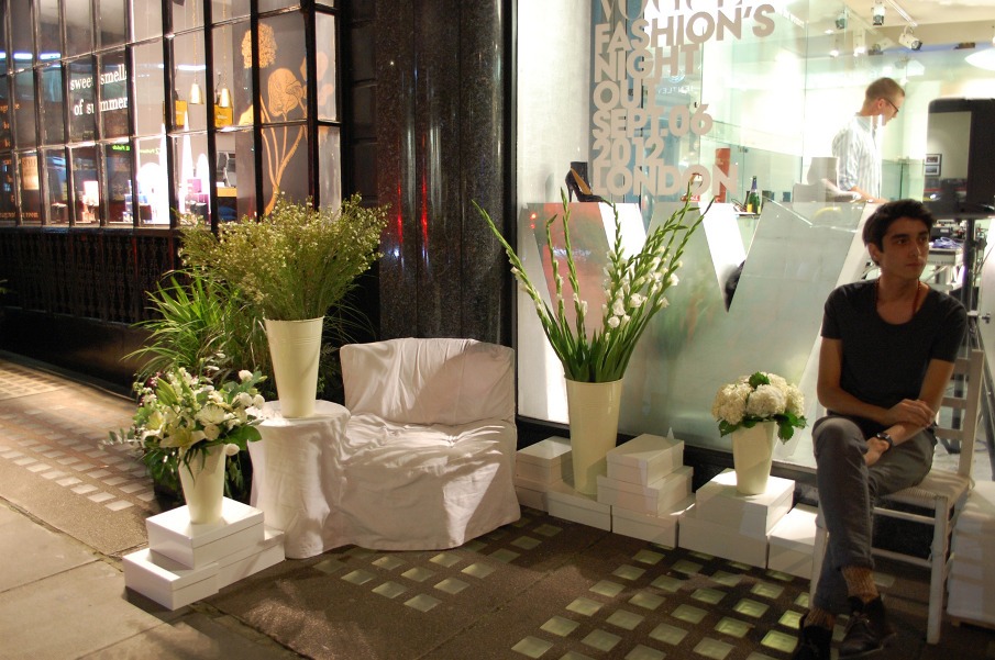 Rincón con sillón forrado de blanco y jarrones de flores junto al escaparate de Maison Martin Margiela