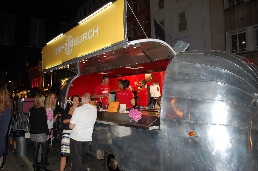 Caravana Airstream plateada con el rótulo Tory Burch sirviendo bebidas en la calle