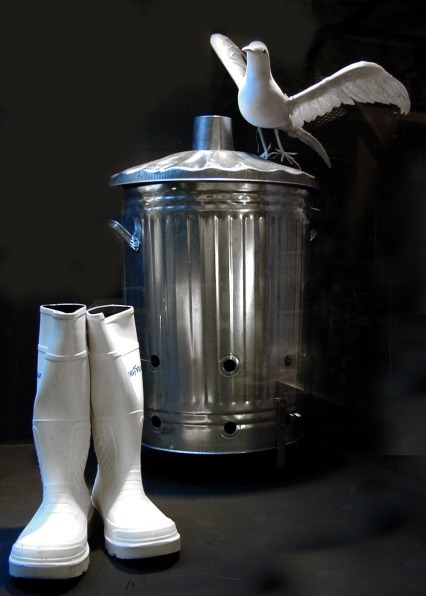 Botas blancas de agua junto a un cubo de basura metálico con una gaviota, en Vinçon