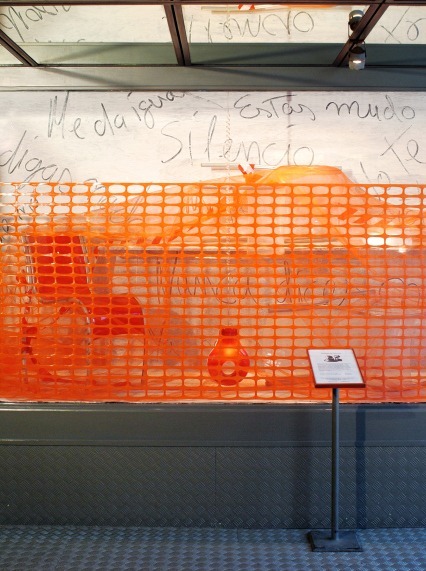Valla de plástico naranja sobre una pared pintada con la palabra silencio en Vinçon