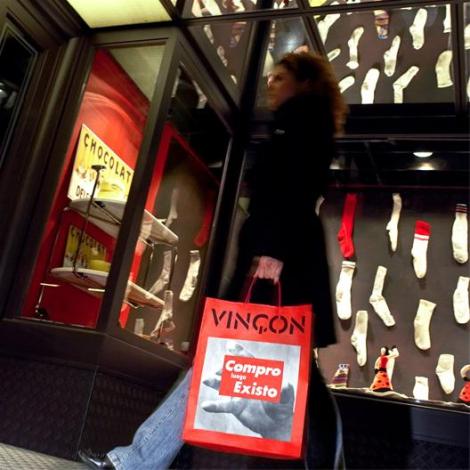 Mujer con una bolsa de Vinçon Compro luego Existo ante un escaparate de calcetines