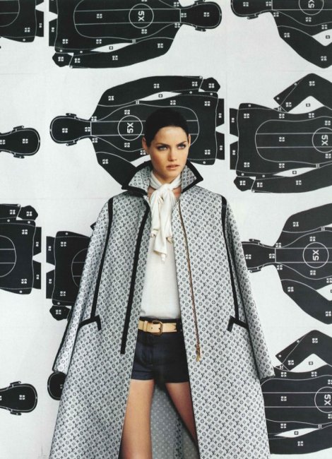 Modelo con capa de monograma Louis Vuitton sobre fondo de patrones de costura