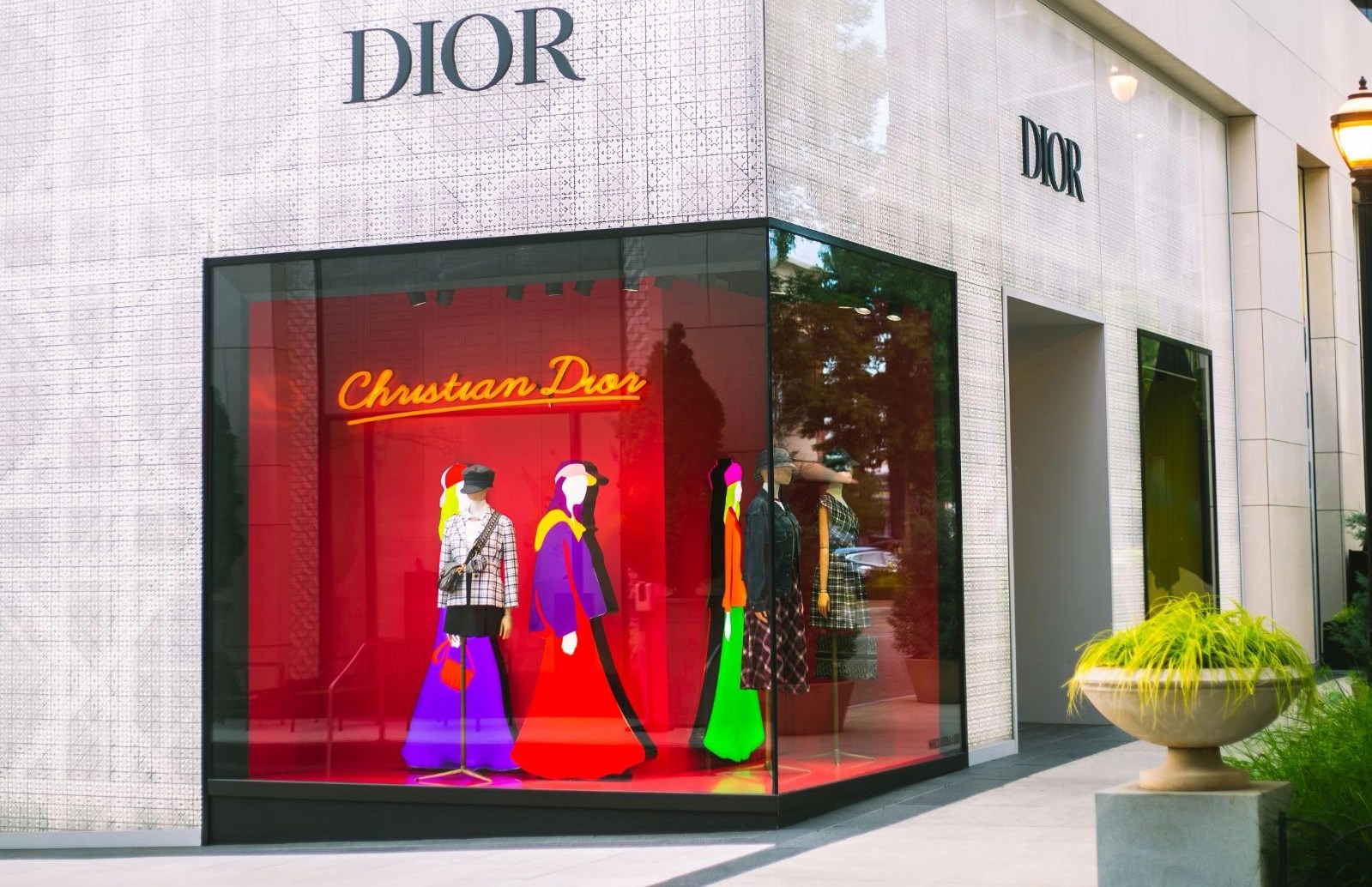 Dior corner window display with illustrated mannequins on a red background