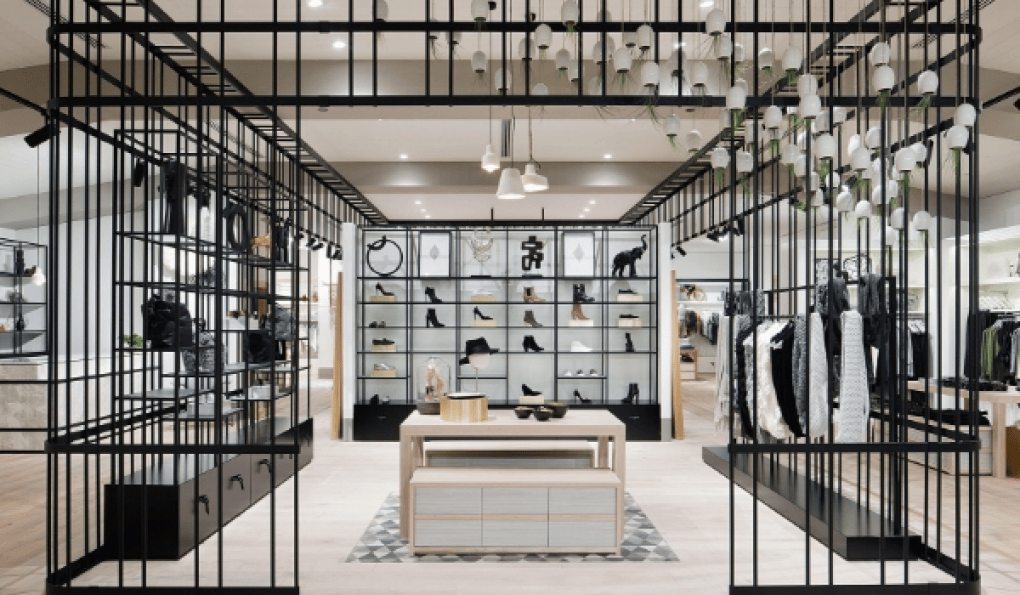Interior de tienda de moda con estanterías en jaula metálica negra y mesa de madera central