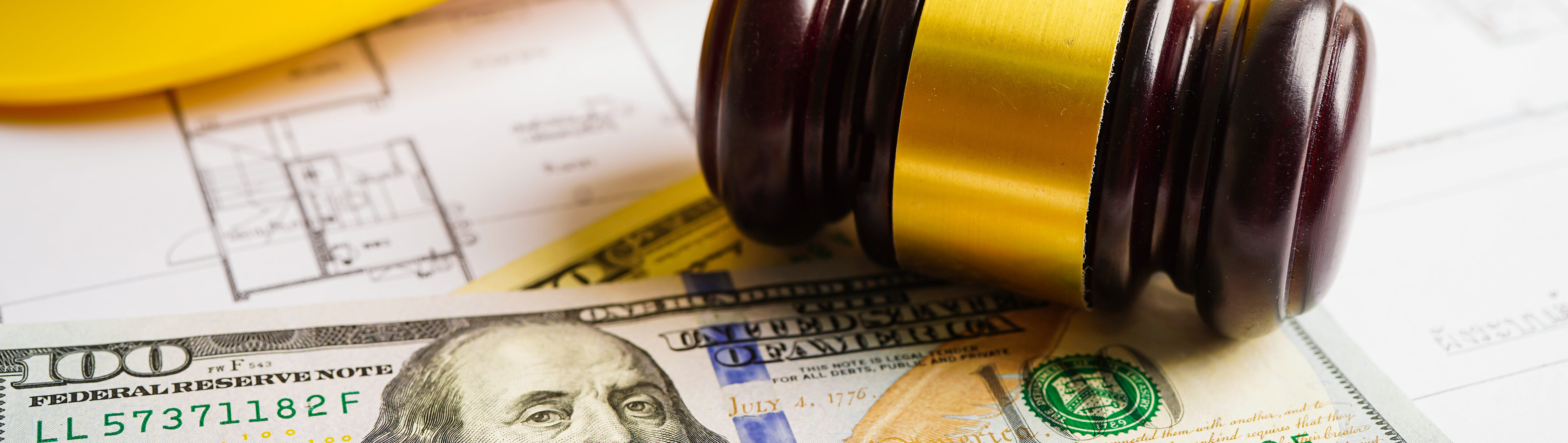 Gavel for judge lawyer with construction helmet and US dollar banknotes money for working project in office.