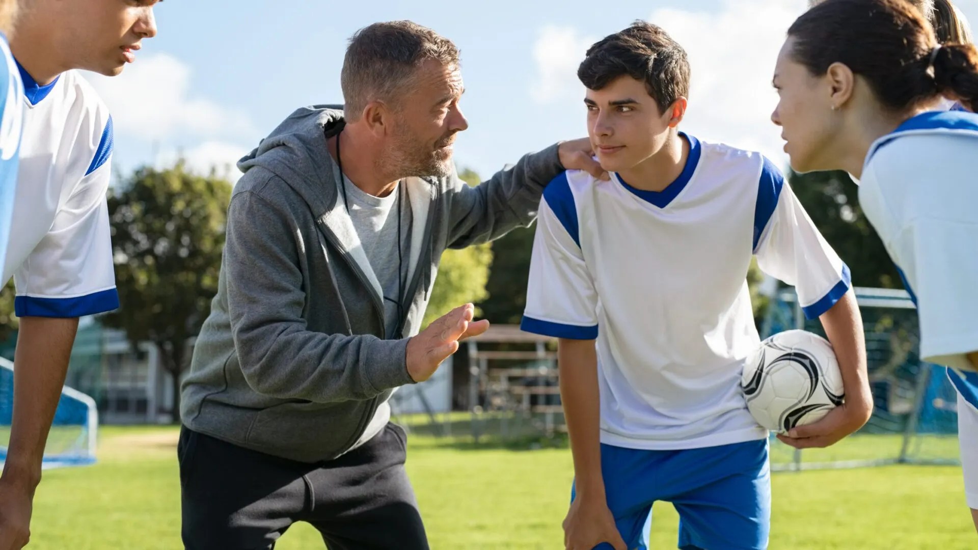Coach talking to a young footballer on the touchline after a difficult match