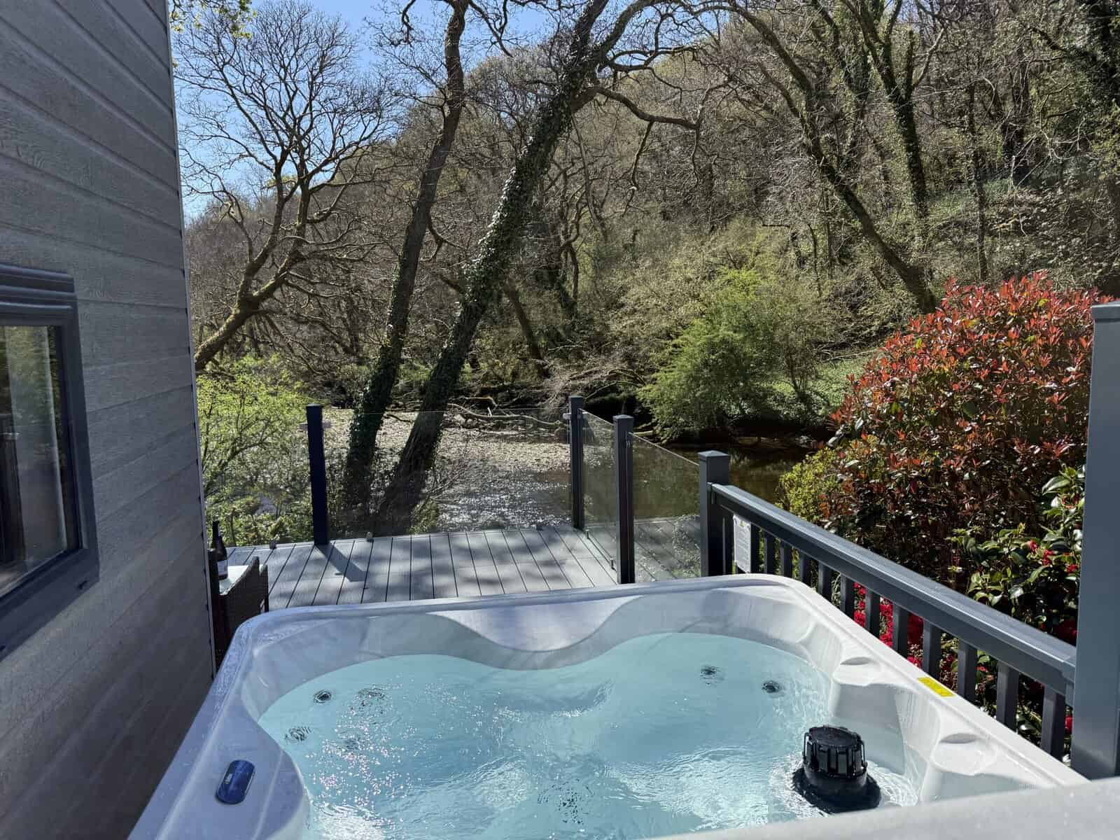 Hot tub on deck overlooking a river and wooded area.