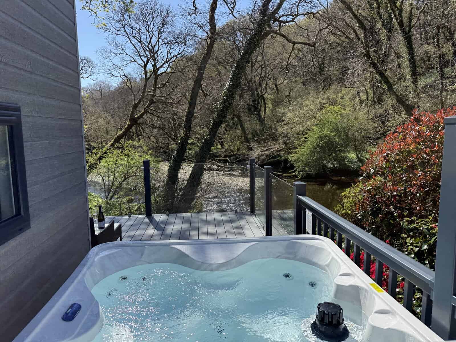 Hot tub on deck overlooking a river and wooded area.