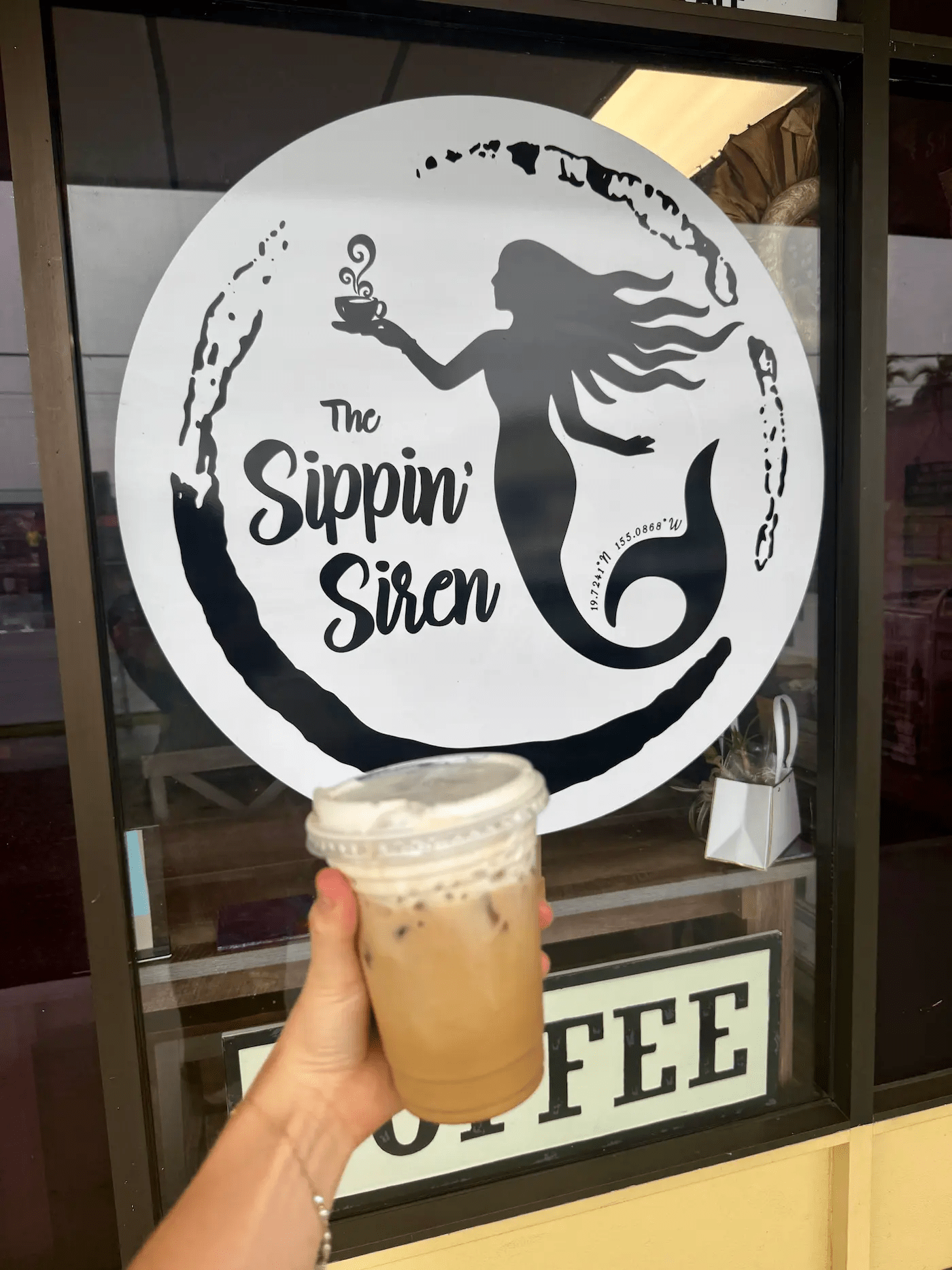 iced latte with cold foam in front of Sippen Siren Coffee Shop 