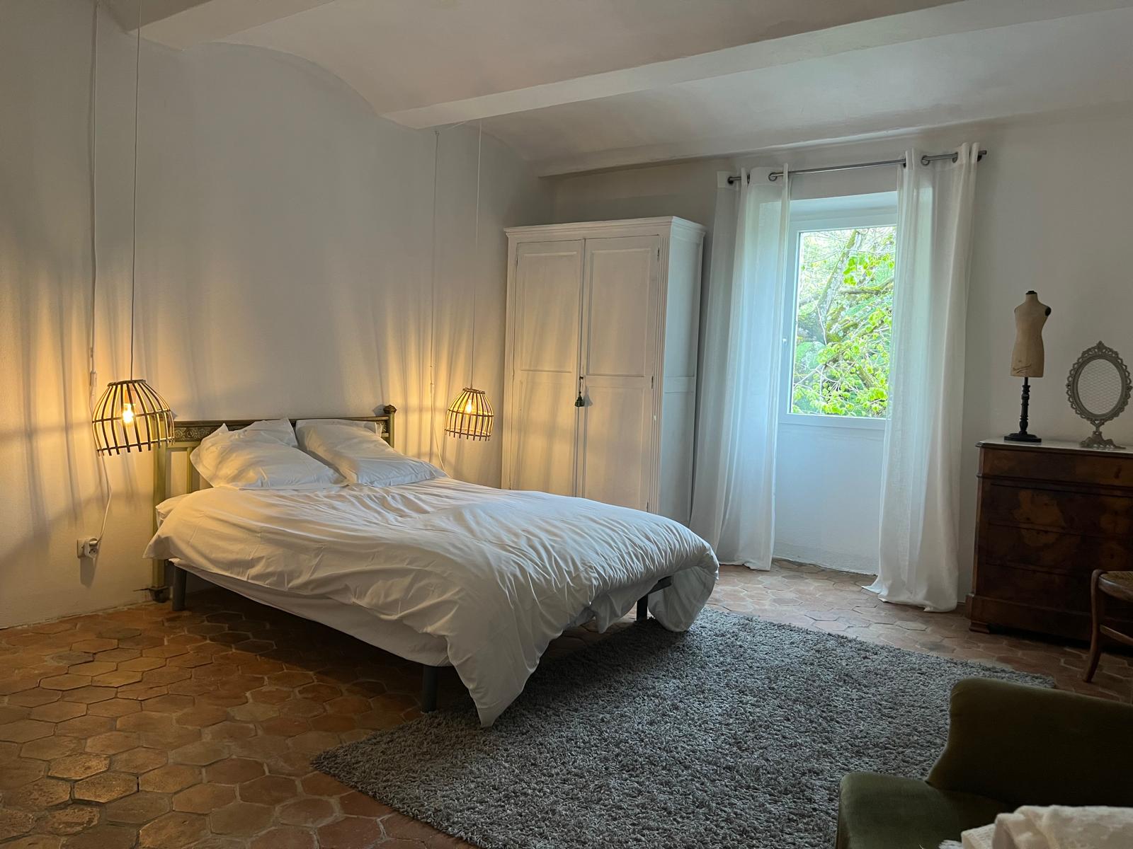 Chambre double avec lit queen-size, linge blanc et décoration chaleureuse dans le mas