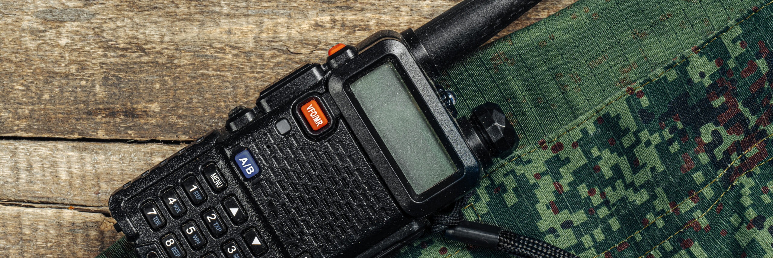 Walkie-talkie and military uniform on wooden surface close up