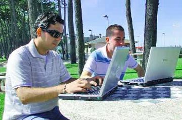 Uns mozos empregando os seus portátiles na praia de Samil
