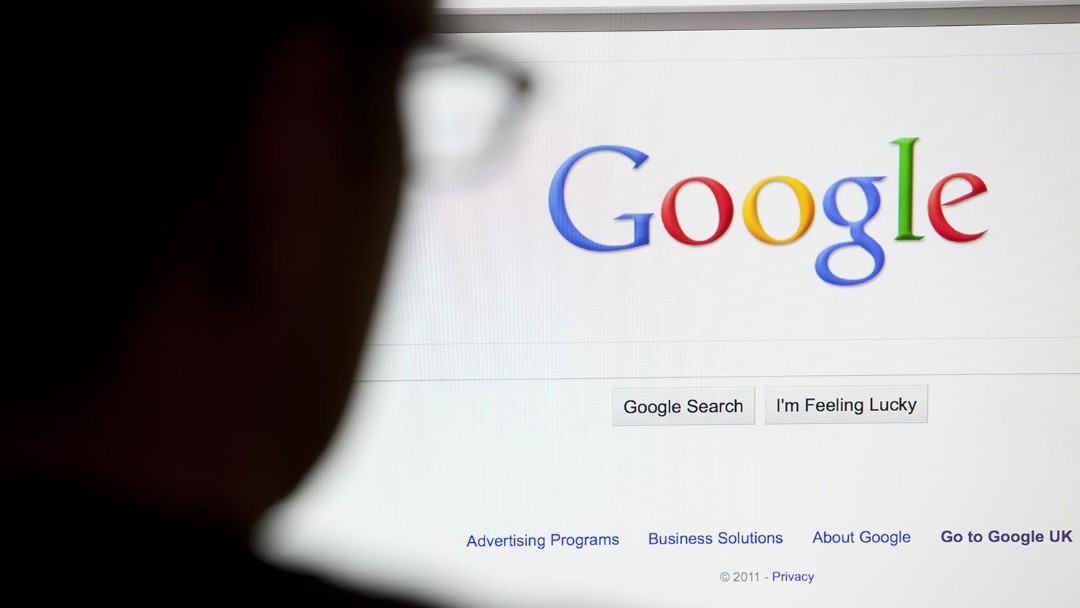Hombre sentado frente a computadora logo Google
