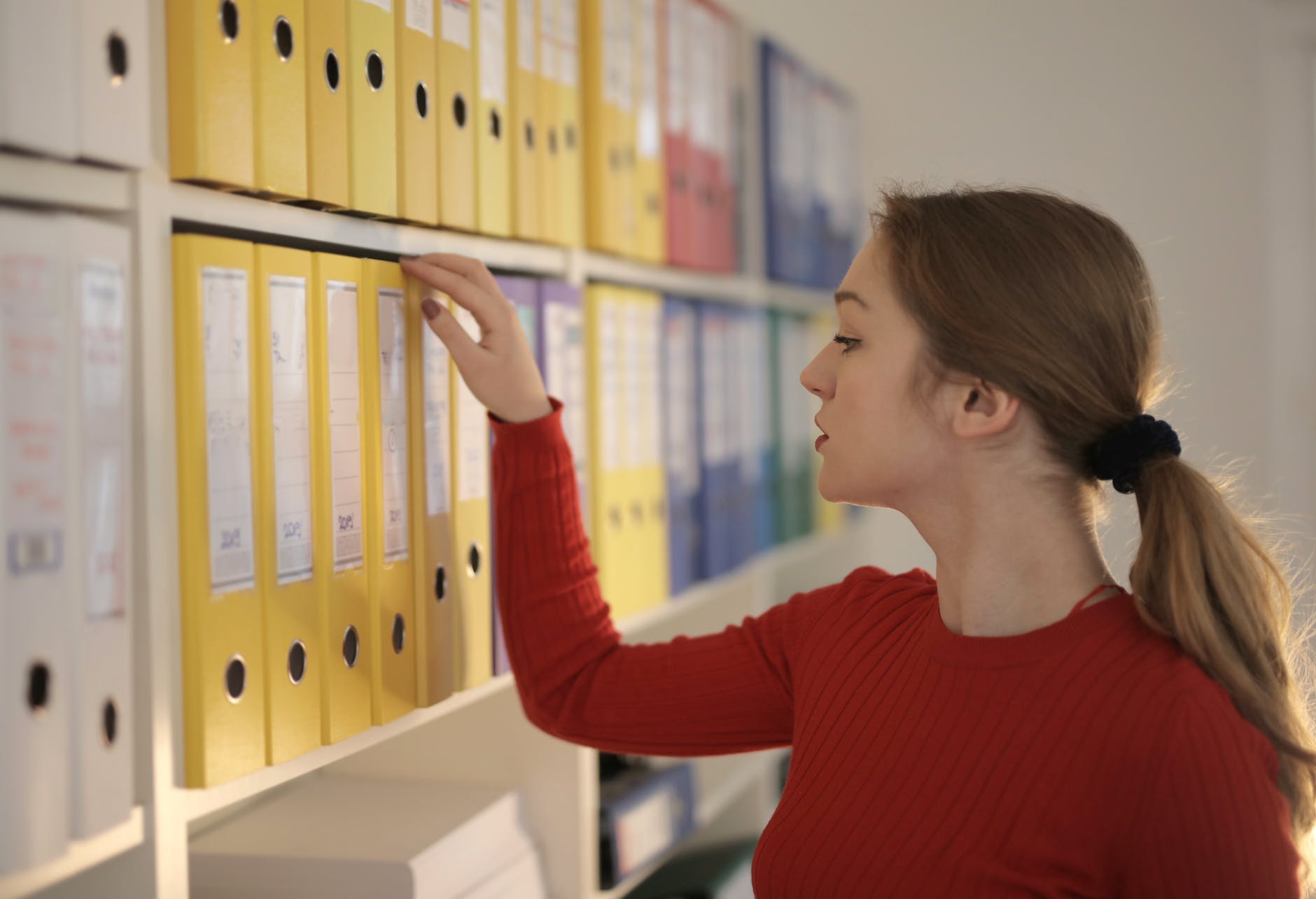 pondering female secretary picking folder in workplace