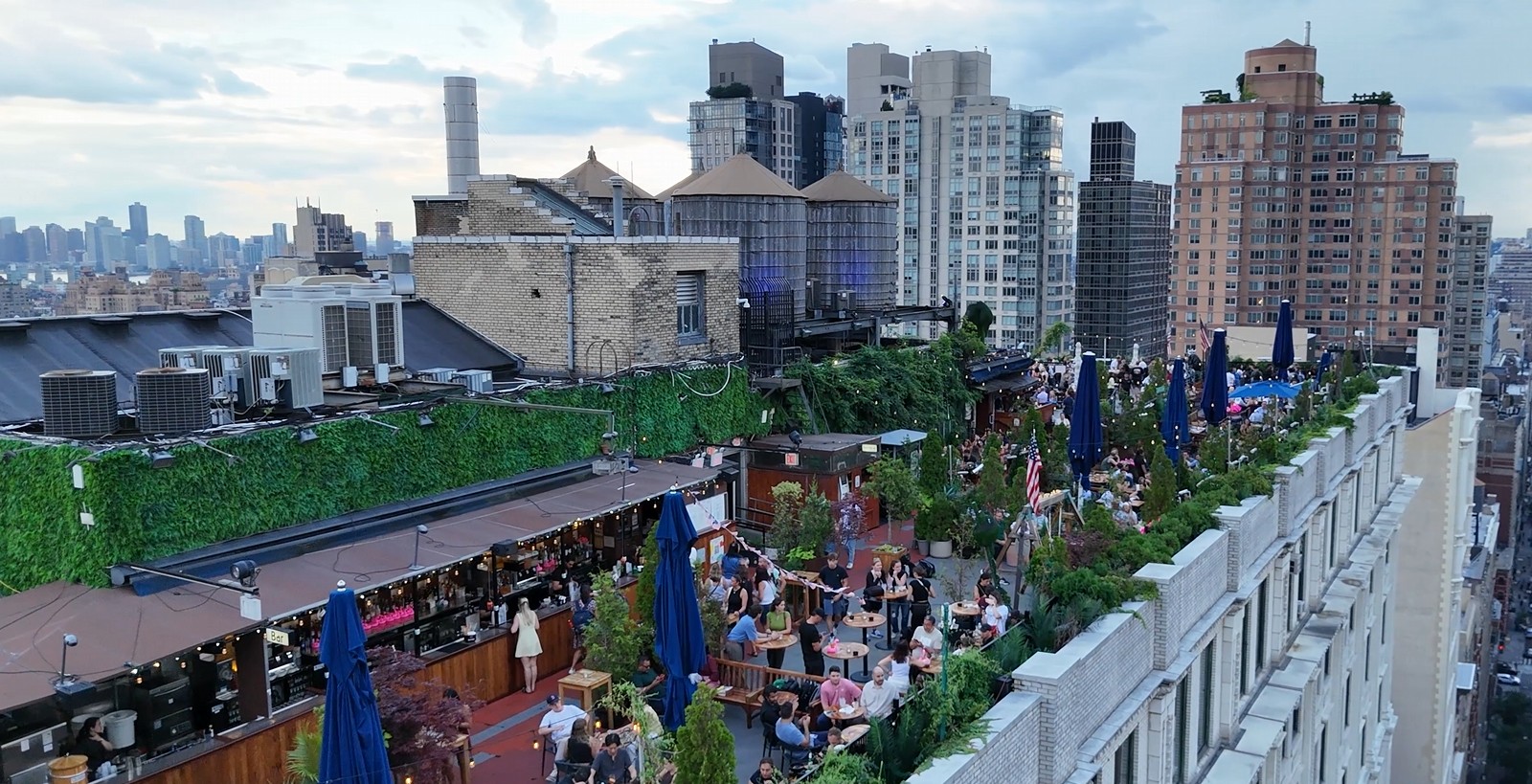 A rooftop bar in Manhattan, NY crowded with people on a summer evening