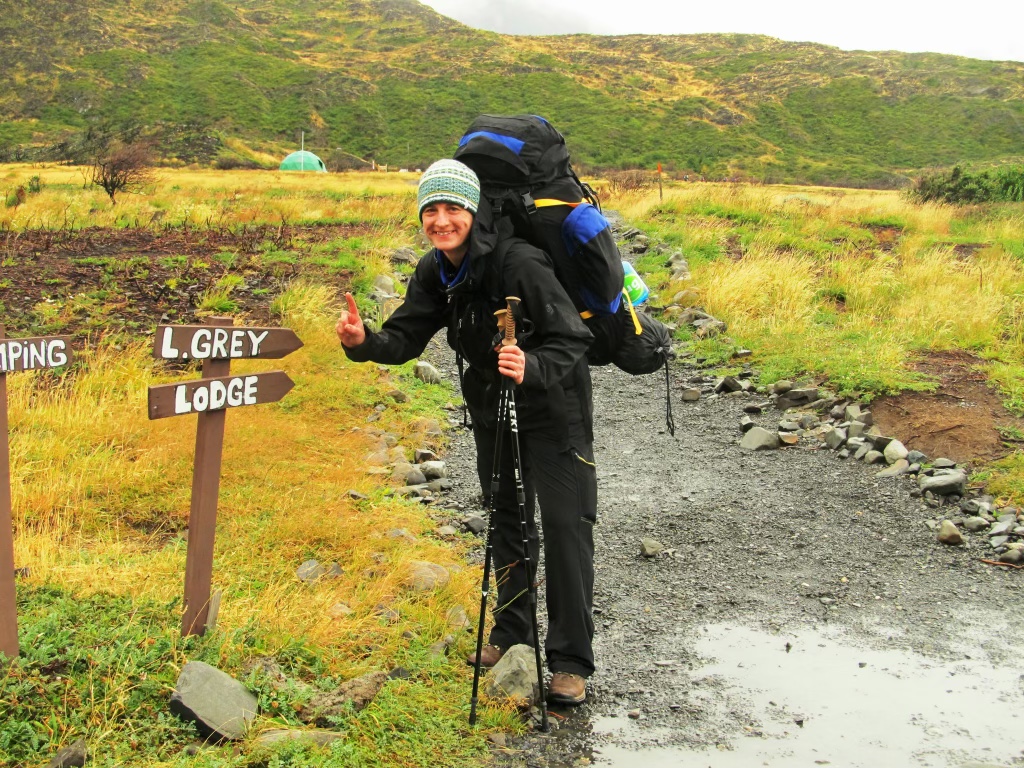 Beth Howland on a camping trip standing by signs pointing in a variety of directions.