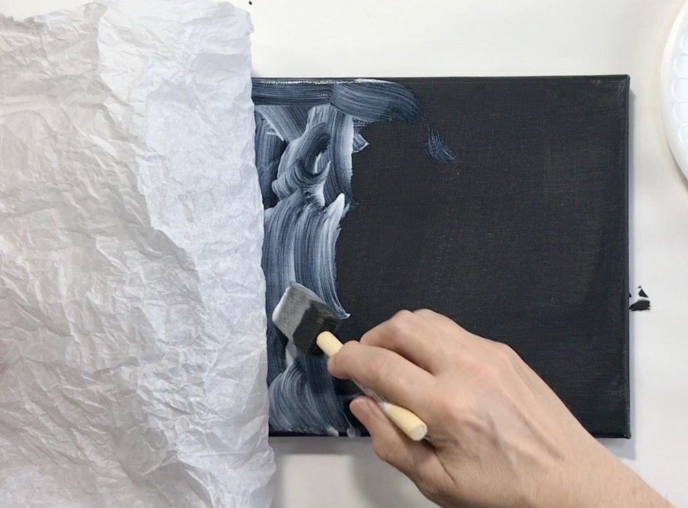 Photo showing the black painted canvas as I am layering on the first bit of decorative tissue paper for today's project.