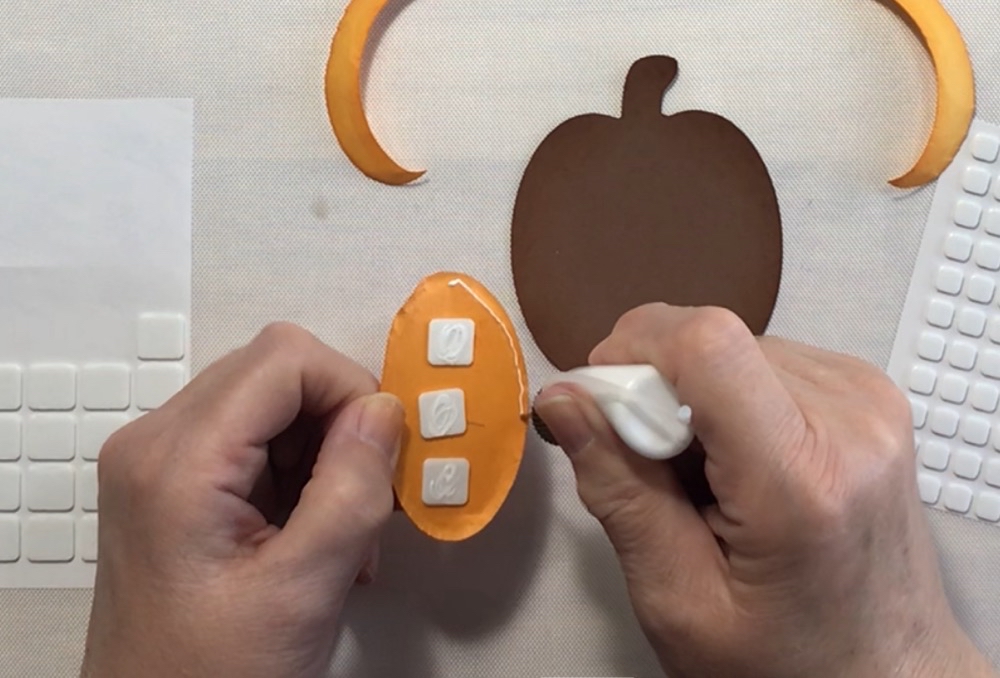 Photo showing the thin 3d foam squares in the center of the pie cut with art glitter glue being applied to the outer edges. 