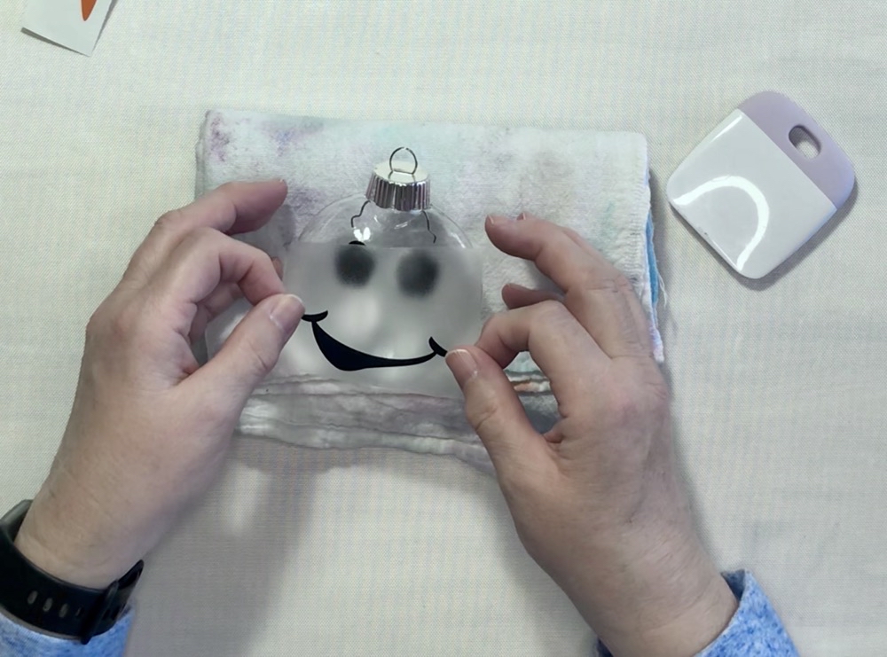 Photo showing applying the mouth to the first snowman ornament after not being able to apply the eyes and mouth at the same time.