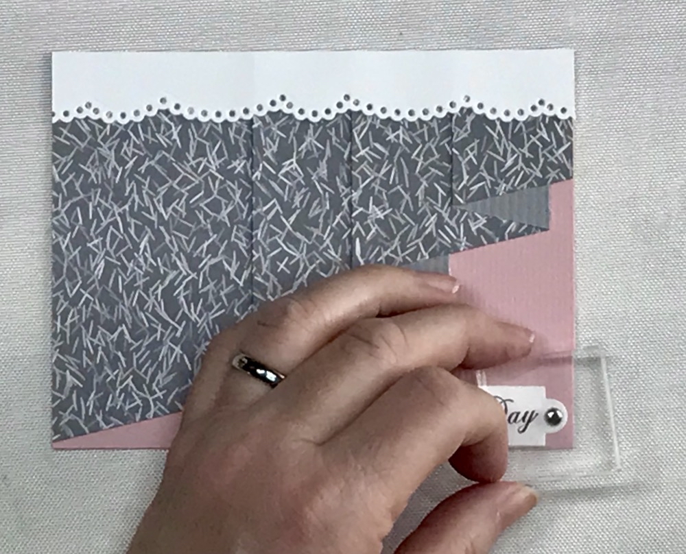Photo showing how I use a small arclyic block to help press down mini brads so they are as flat as possible.