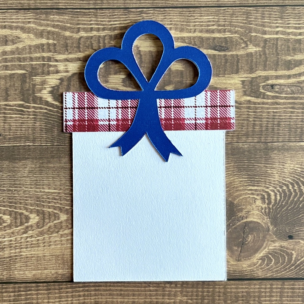 Photo of another finished gift tag featuring Recollections cardstock, pattern paper from the Hobby Lobby Winter Berry paper pad and a piece of metallic blue paper.