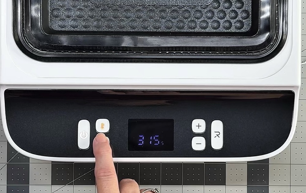 Photo showing the yellow light on the temperature button to set the temperature of the top heat plate.