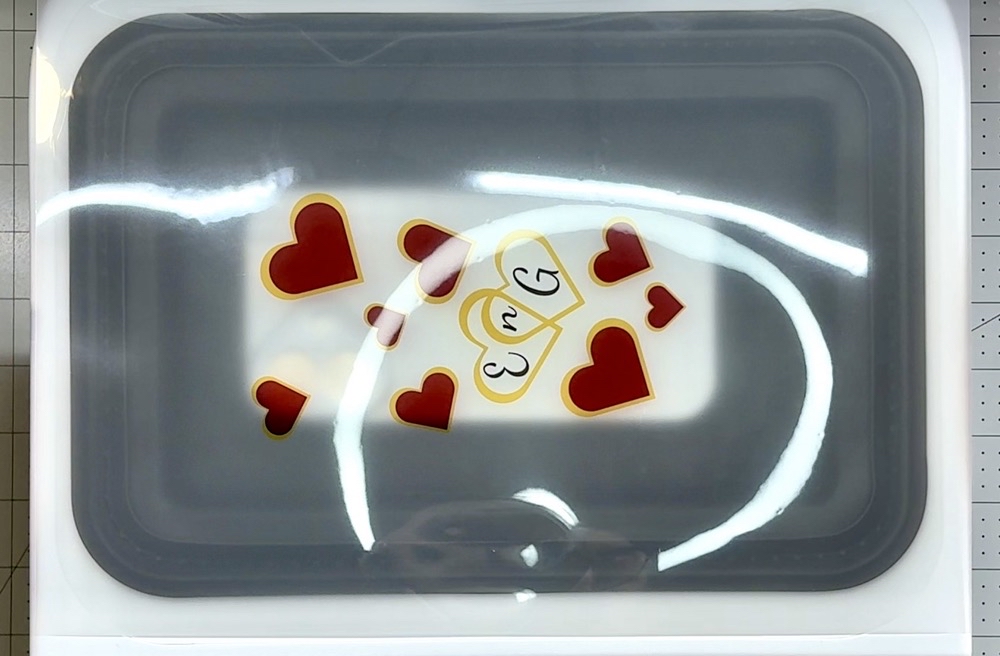 Photo showing the printed image in the heat press ready to be sublimated for today's Interlocking Hearts Phone Case with the HTVRont Press post.