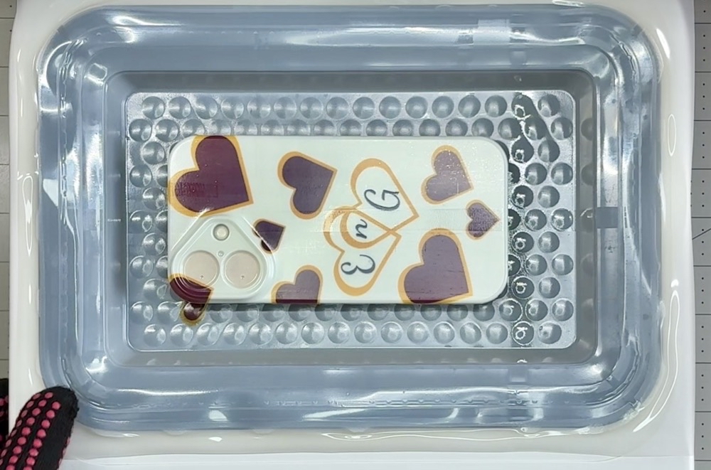 Photo showing the sublimation film after being pressed in the HTVRont Phone Case Heat press. 