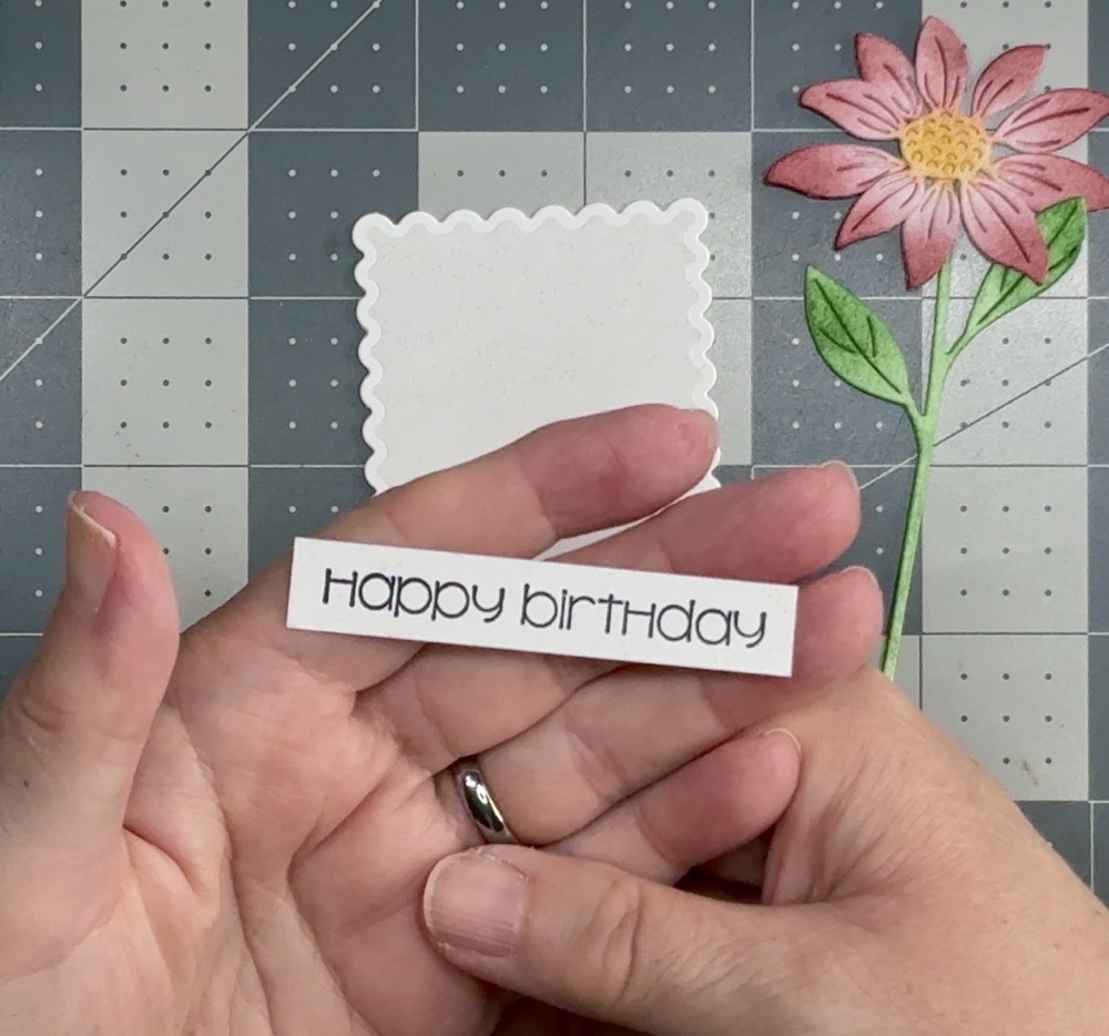 Screen shot showing the newly cut, inked, and stamped sentiment strip after realizing the first on had a pink tinge to it from the Aged Mahogany distress ink on the Teflon mat.