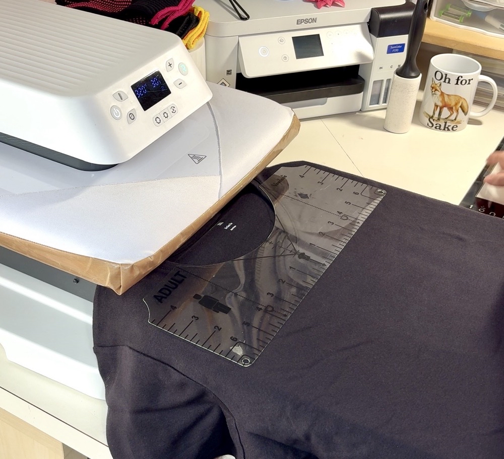 Photo showing the use of a t-shirt ruler to assist in centering the DIY Sister Shirts with HTV design for todayโs project.