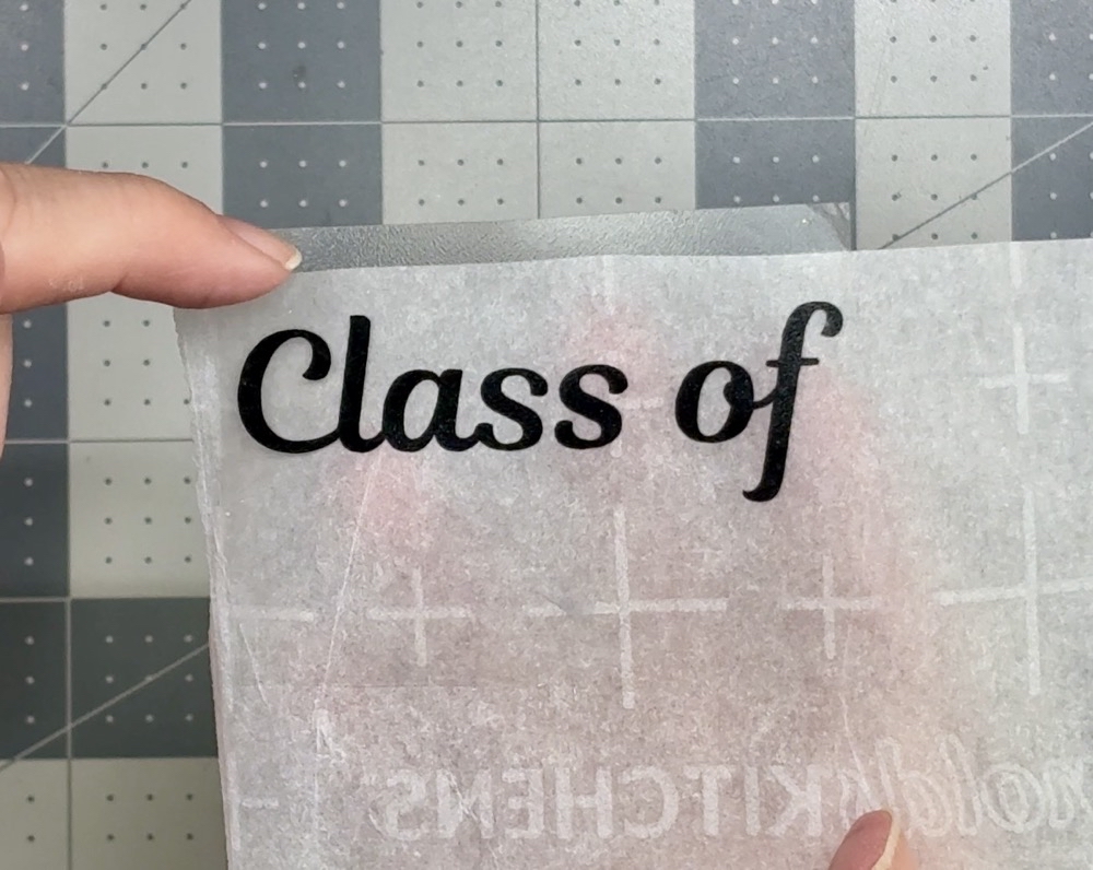 Screen shot showing the transfer tape and vinyl stuck to a piece of parchment paper with a bit of the transfer tape hanging over the edge to assist in the application to the front of the card.