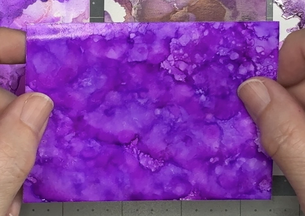 Screen shot of a scrap piece of white Oracal 651 permanent vinyl with alcohol inks applied in Purple Twilight, Wild Plum and Pearl Mixative.