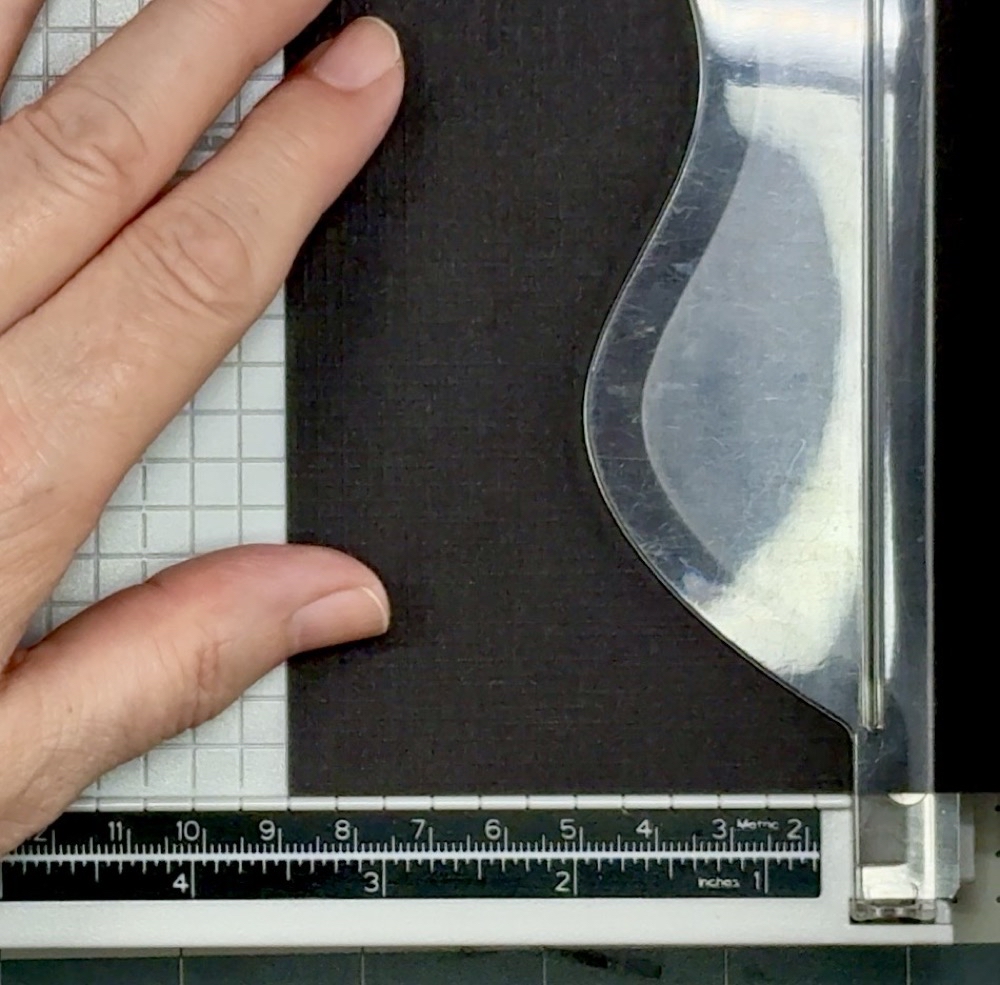 Screen shot showing the black linen-textured card stock being cut to a width of 3 ½” as mats for the alcohol ink strips.