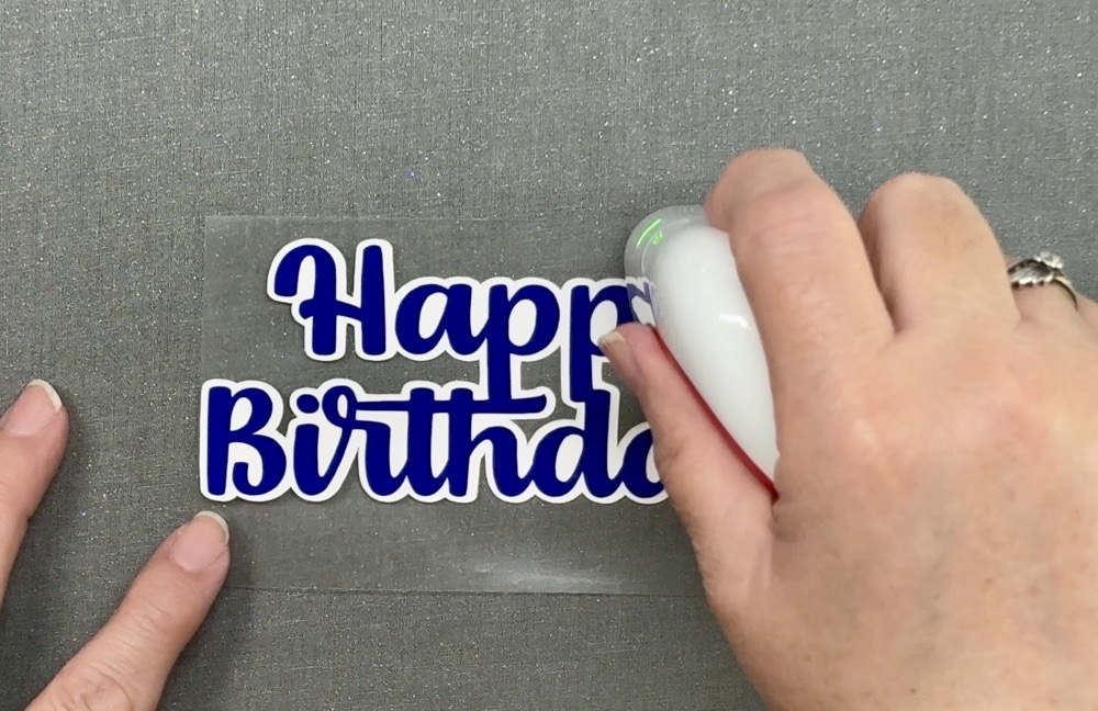 Screen shot showing using the Cricut Easypress Mini applying heat to the HTV for today's Easy Birthday Cake Topper with Cricut project.