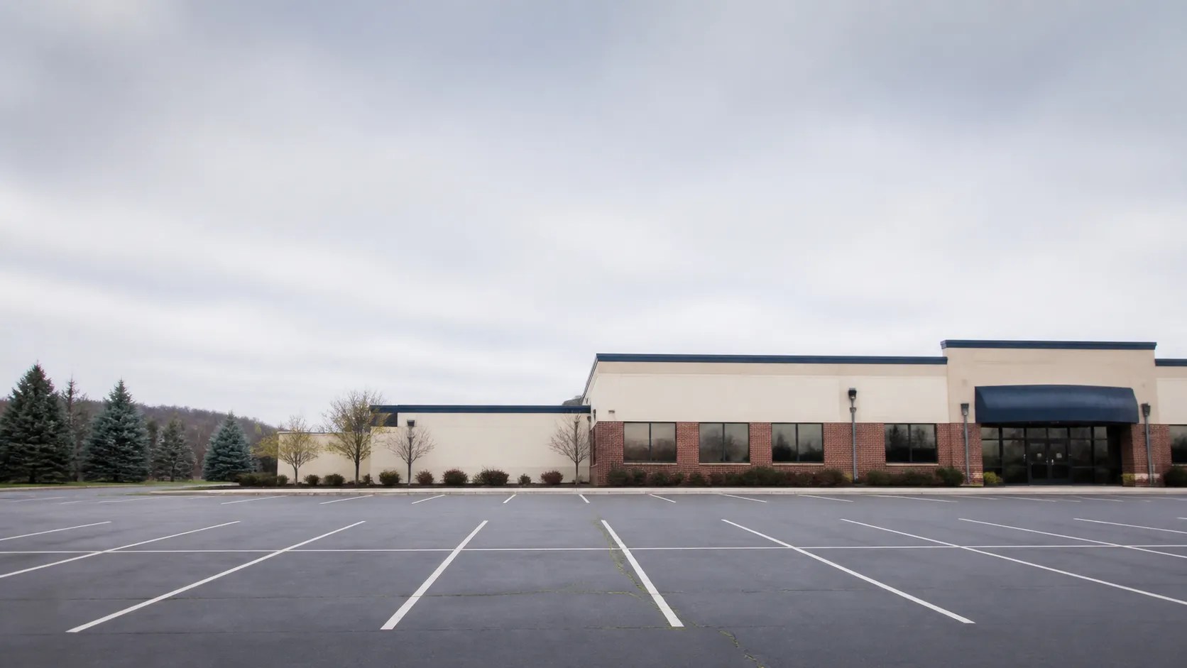 Large empty striped parking lot in front of a low commercial building in New England.