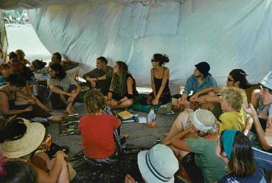 A group of students hold a discussion in a tent.
