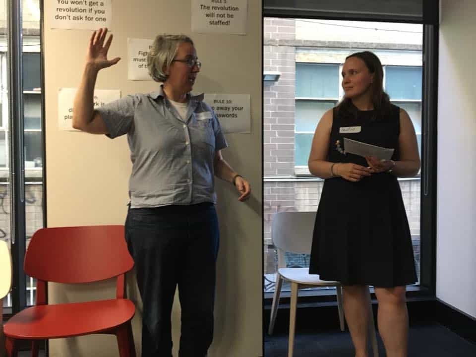 Two women stand together talking.