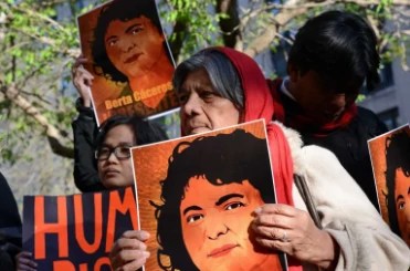 People at a memorial hold up images of Berta Caceres