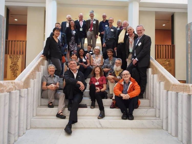 A large group of people sitting and standing on a grand, marble staircase. 