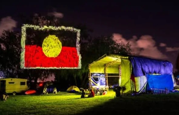 Projection of an Aboriginal flag onto trees.