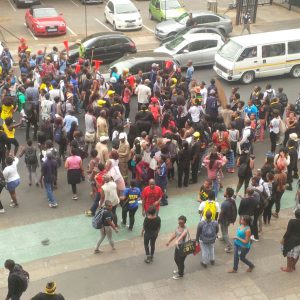 A group of people filling a street and stopping traffic.