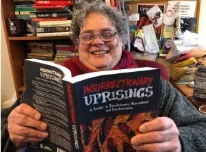 Wende marshall smiling and reading the book Insurrectionary Uprisings.