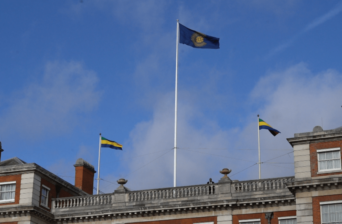Gabon suspended from Commonwealth. Gabon and Commonwealth Flags fly over building.
