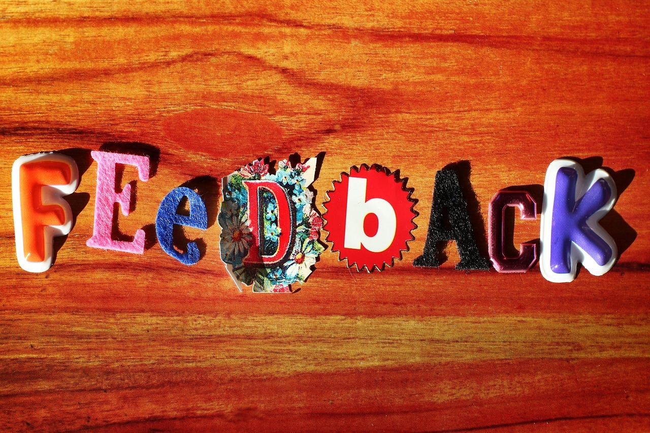 honey colored wood background. the word feedback is spelled out across the middle of the wood, with each letter being a cutout in a different pattern or texture.