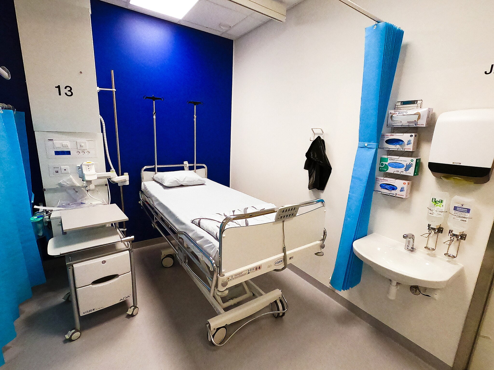 Photo of a hospital room with an empty bed
