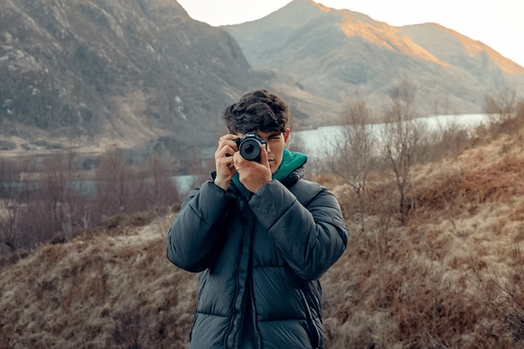 Photographer using a Canon camera in a mountain landscape