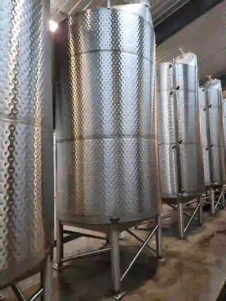Tall dimple-jacketed stainless wine tanks standing in a row on legs in the Augusta Vin cellar